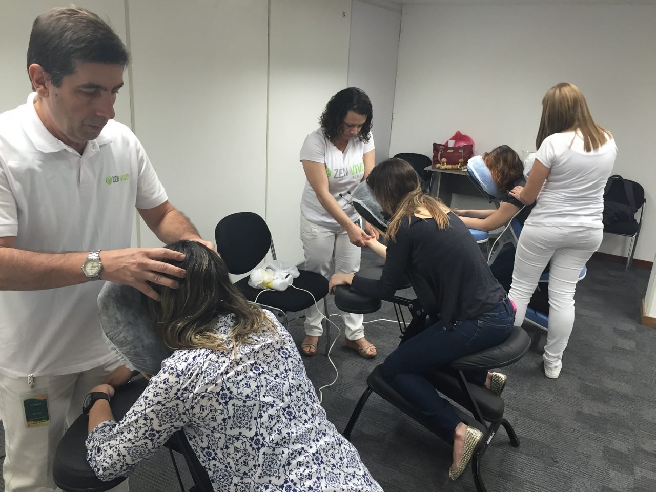 Colaboradores recebendo quick massage em cadeira ergonômica durante evento corporativo, no Rio de Janeiro — serviço de massagem expressa para empresas e SIPAT.
